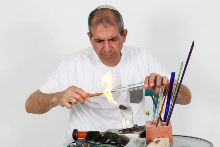 גבר מבצע הדגמה של עבודה עם אש וניפוח זכוכית.